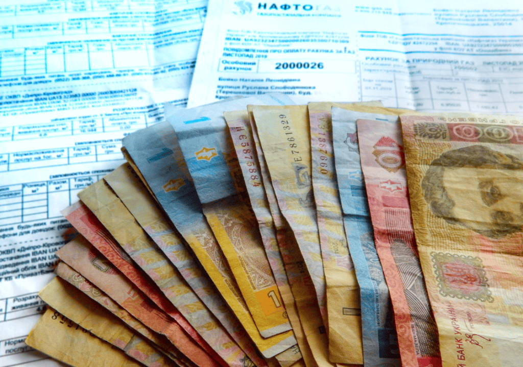 на фото зображено гроші та платіжки за комунальні для пенсіонерів
